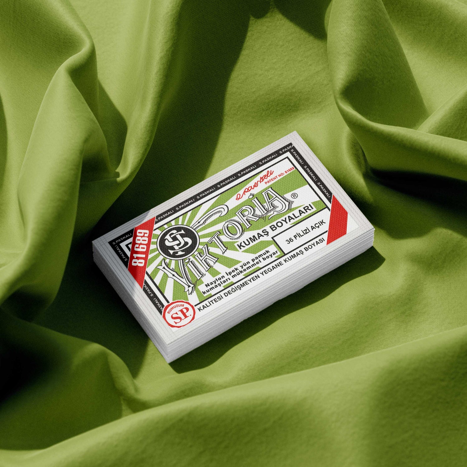 Pack of pistachio green fabric dye placed on a vibrant light green fabric background